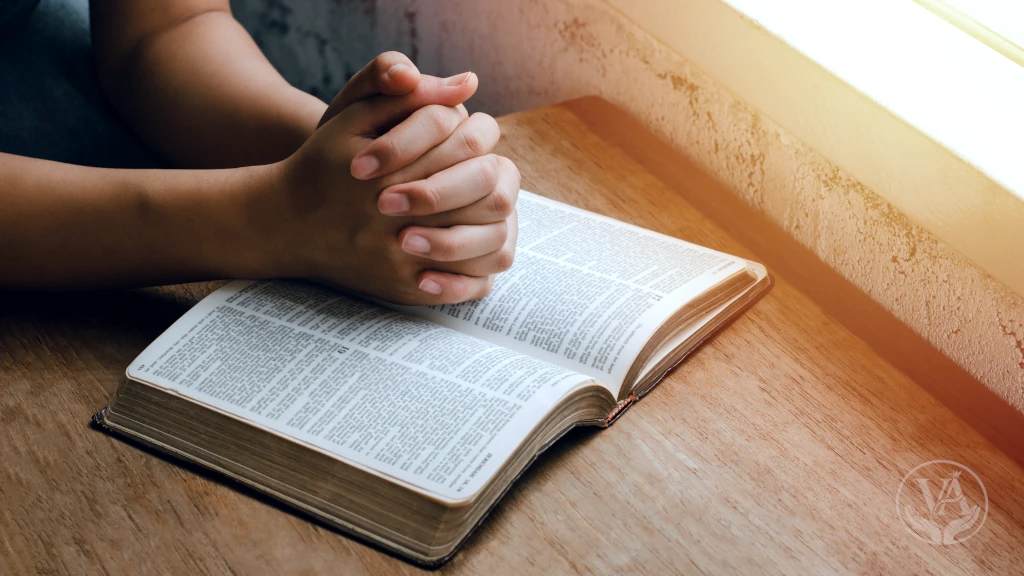 Mãos sobre a Bíblia aberta durante leitura diária e meditação cristã.