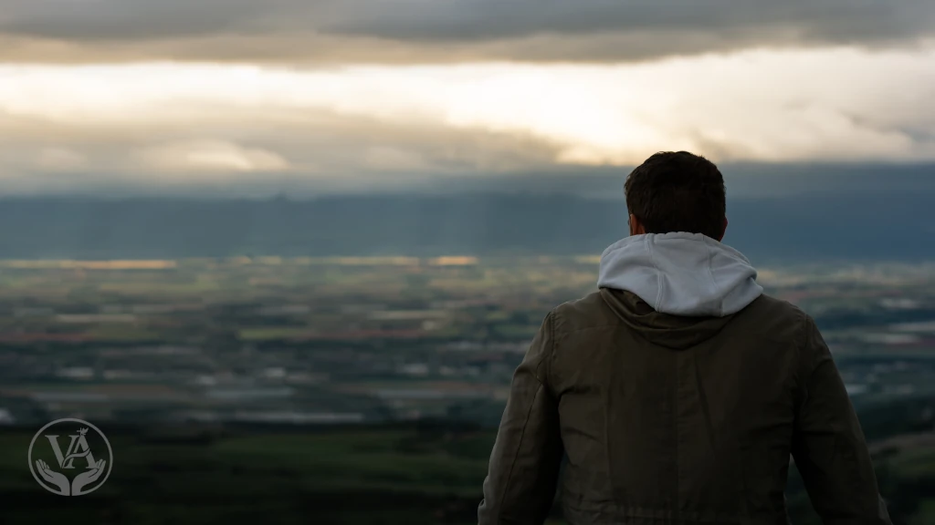 Um homem em pé olhando para o horizonte meditando no silencio sobe as coisas de Deus